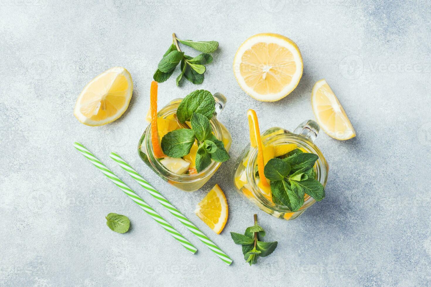 Lemonade drink of soda water, lemon and mint leaves in jar on light background. photo