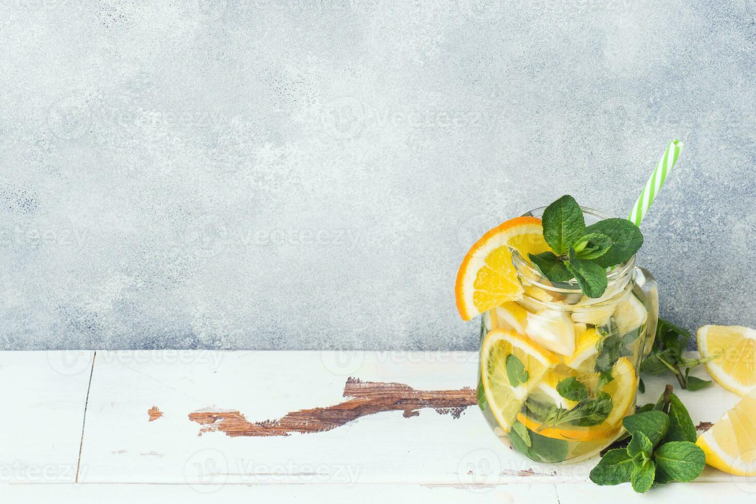 Lemonade drink of soda water, lemon and mint leaves in jar on light background. Copy space photo