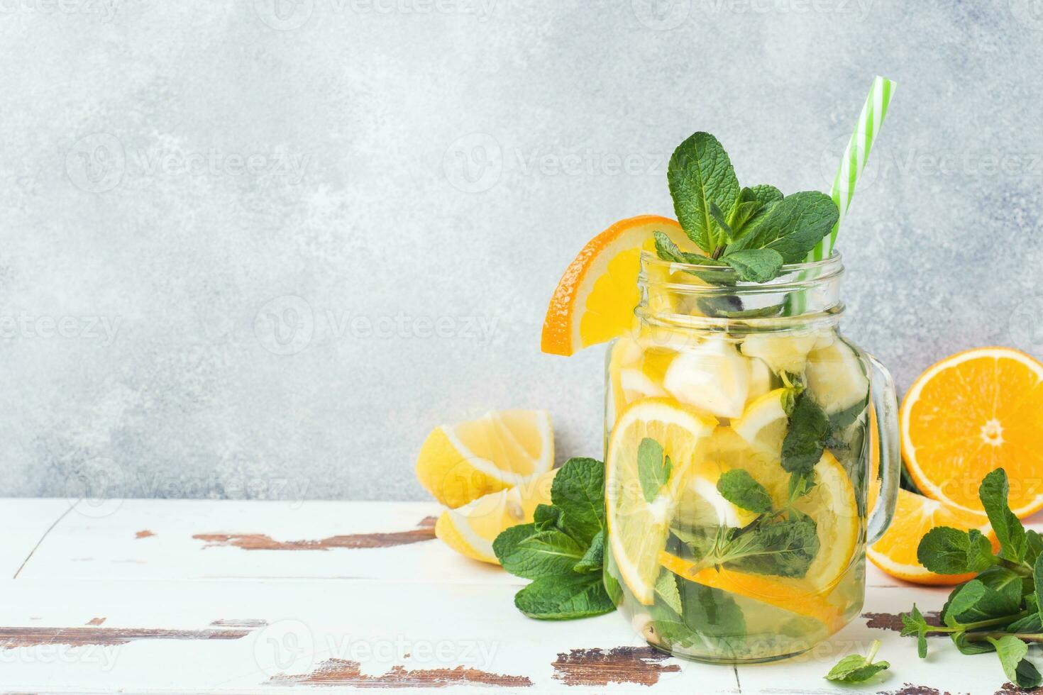 Lemonade drink of soda water, lemon and mint leaves in jar on light background. Copy space photo