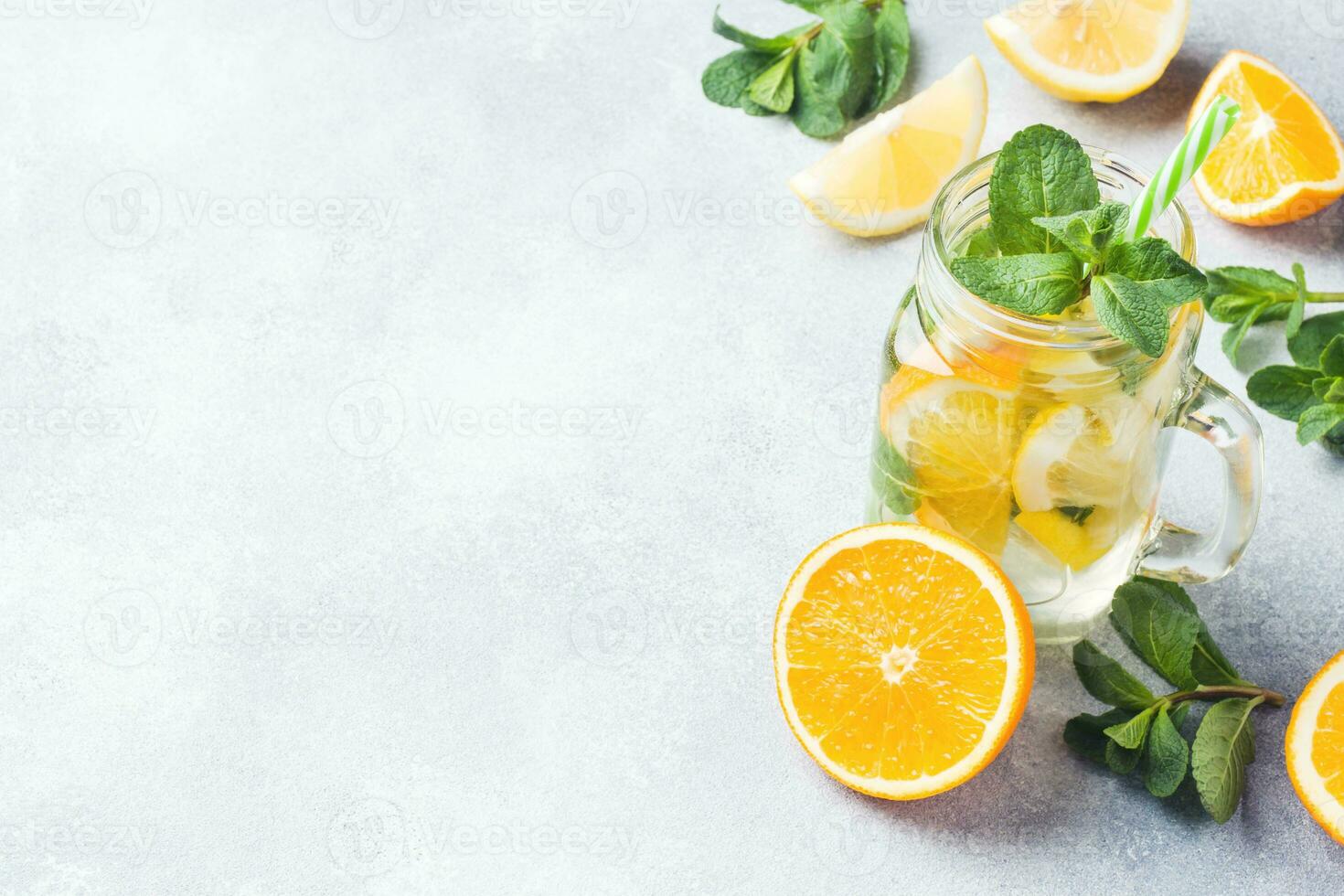 Lemonade drink of soda water, lemon and mint leaves in jar on light background. Copy space photo