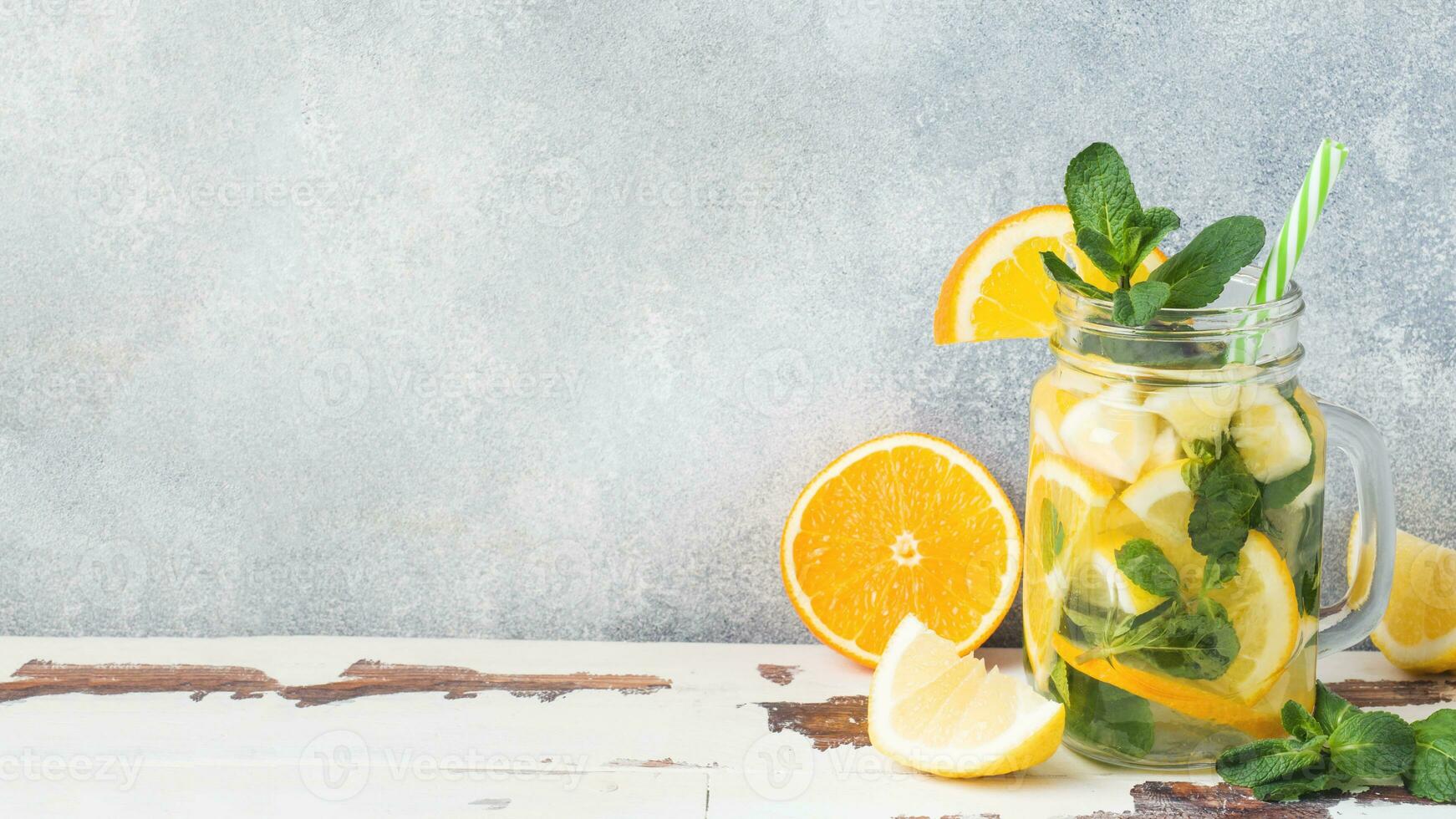 Lemonade drink of soda water, lemon and mint leaves in jar on light background. Copy space photo