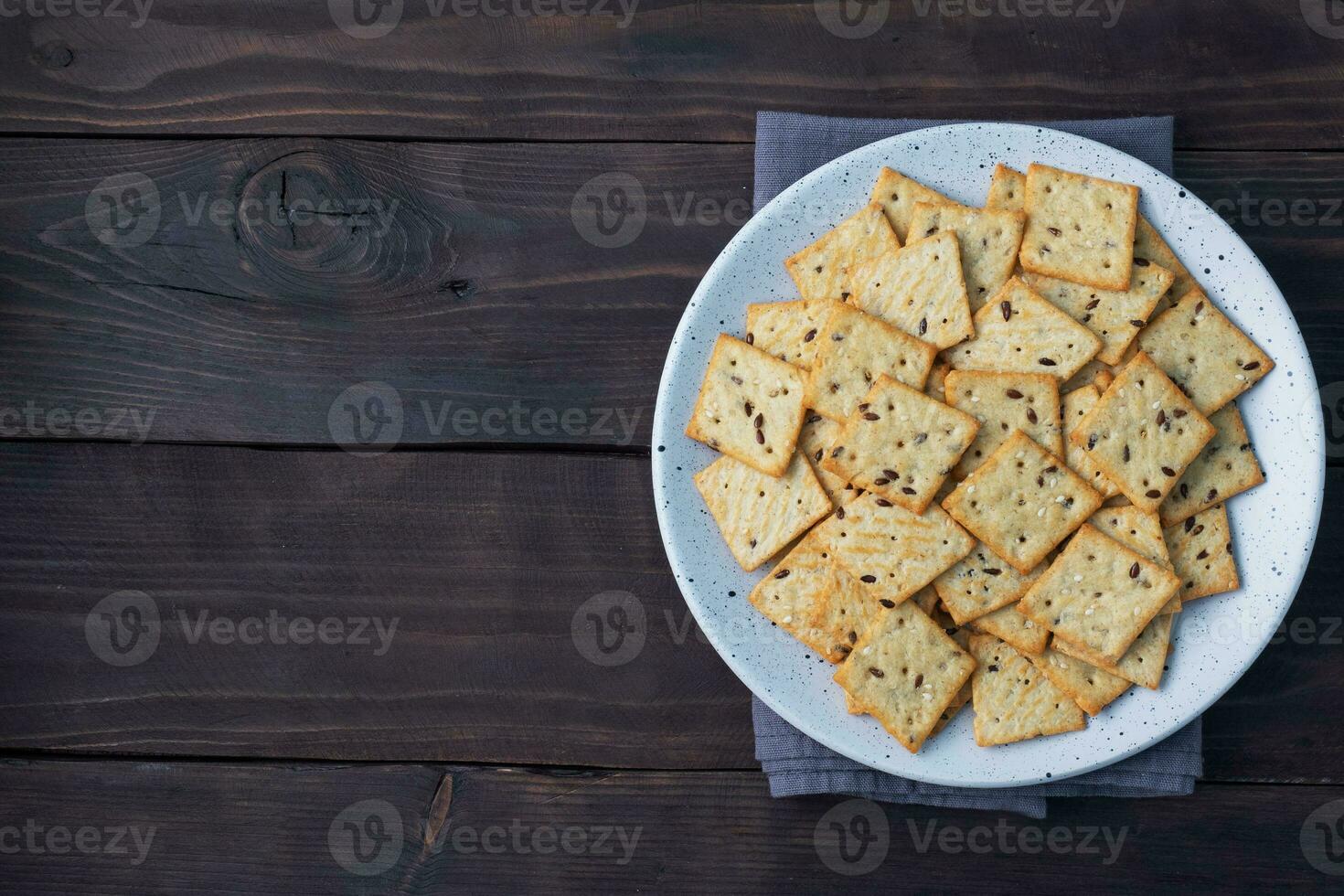 Delicious healthy cookies crackers with flax seeds and sesame seeds on a plate. Background of a healthy snack food, dark rustic wooden table. Copy space. photo