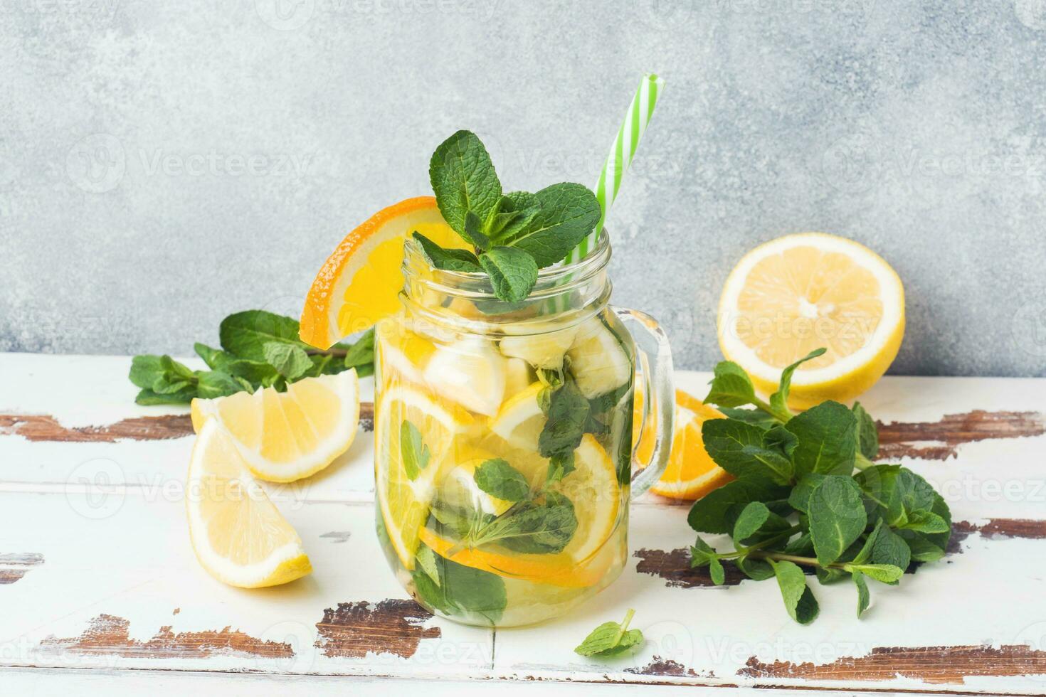Lemonade drink of soda water, lemon and mint leaves in jar on light background. Copy space photo