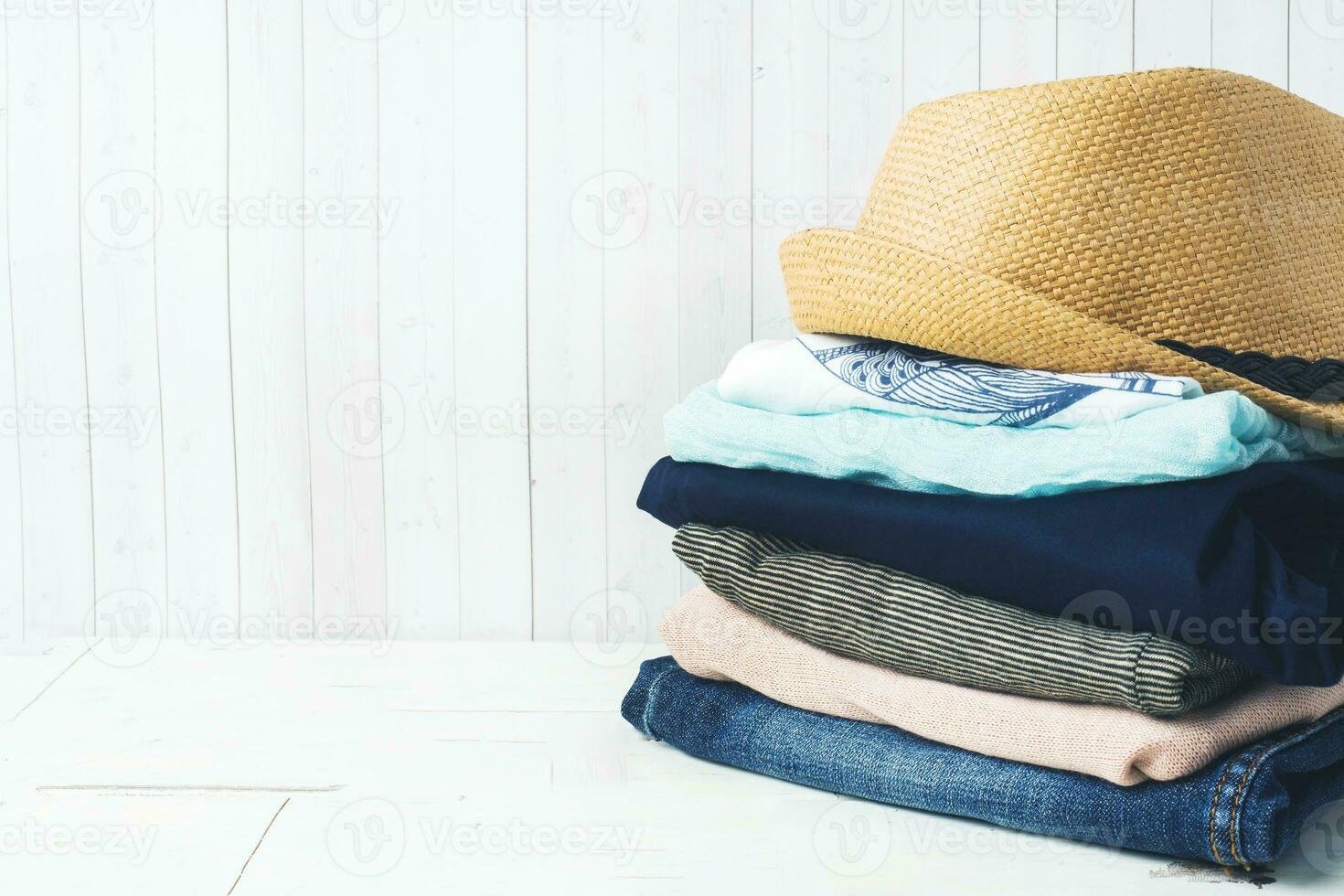 A stack of women's clothing and a straw hat on white boards with a copy of space. photo