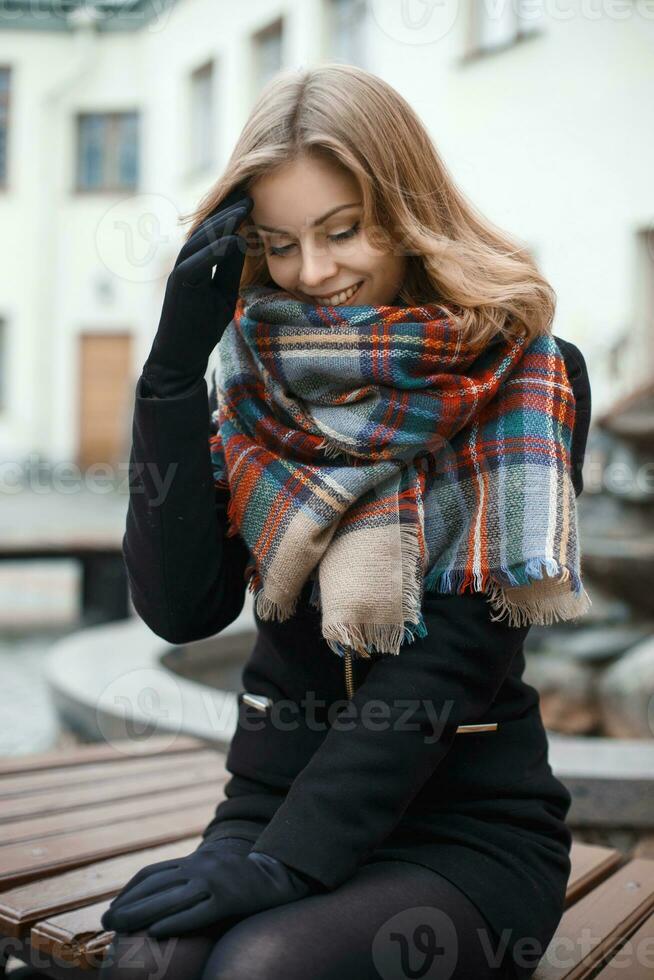 bonito mujer en elegante ropa sentado en un banco en otoño día foto