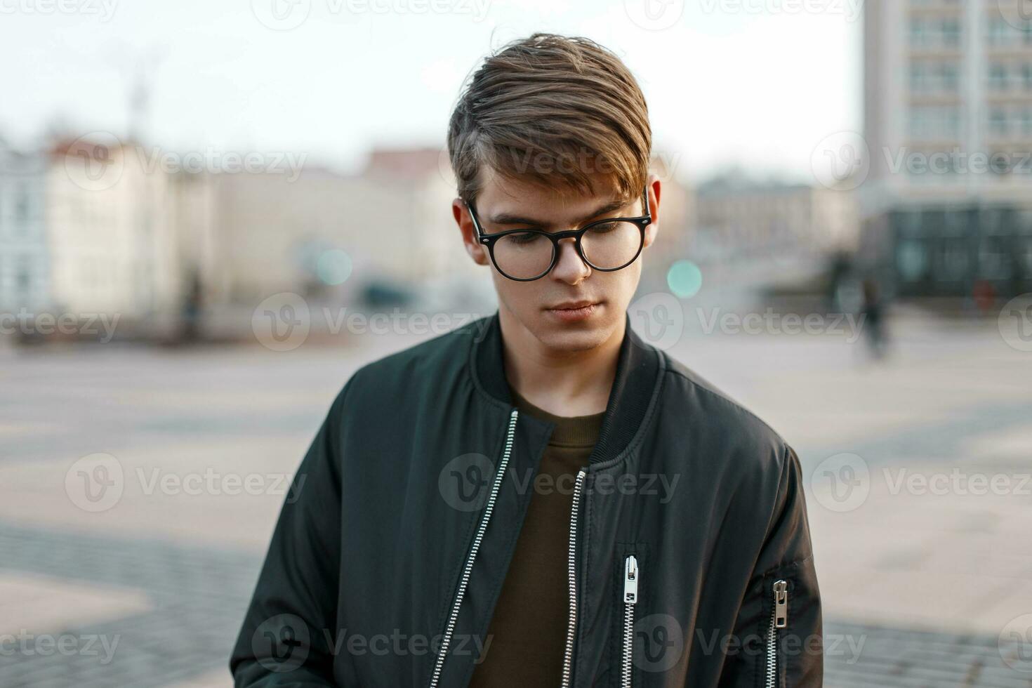 Handsome young man with glasses on the background of the city photo