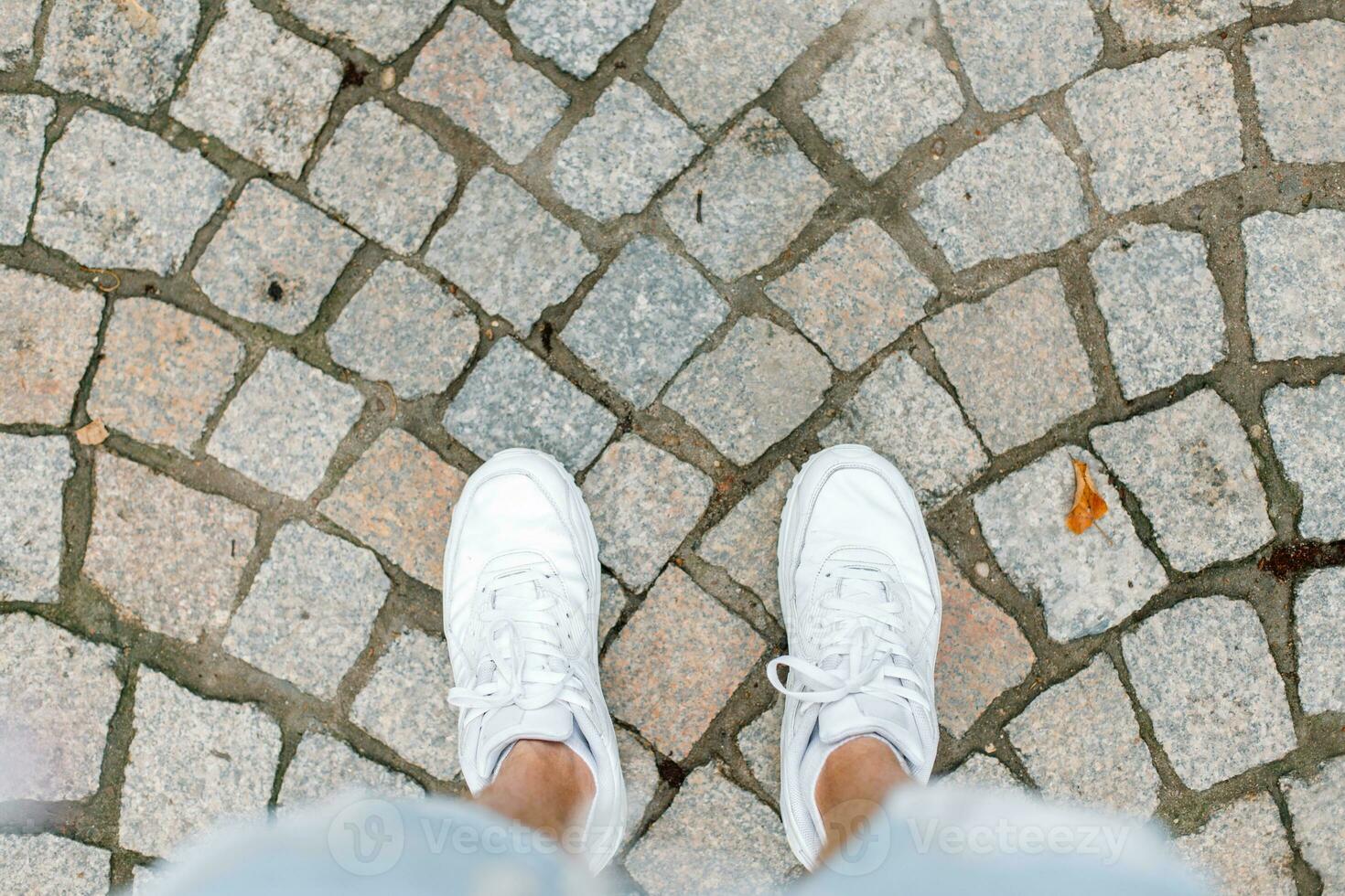 Young man traveling on summer vacation. White sneakers on tile. photo