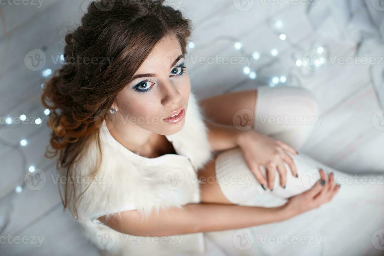 Young pretty woman in a white knitted socks sitting on the floor on a background of lights.. Top view photo