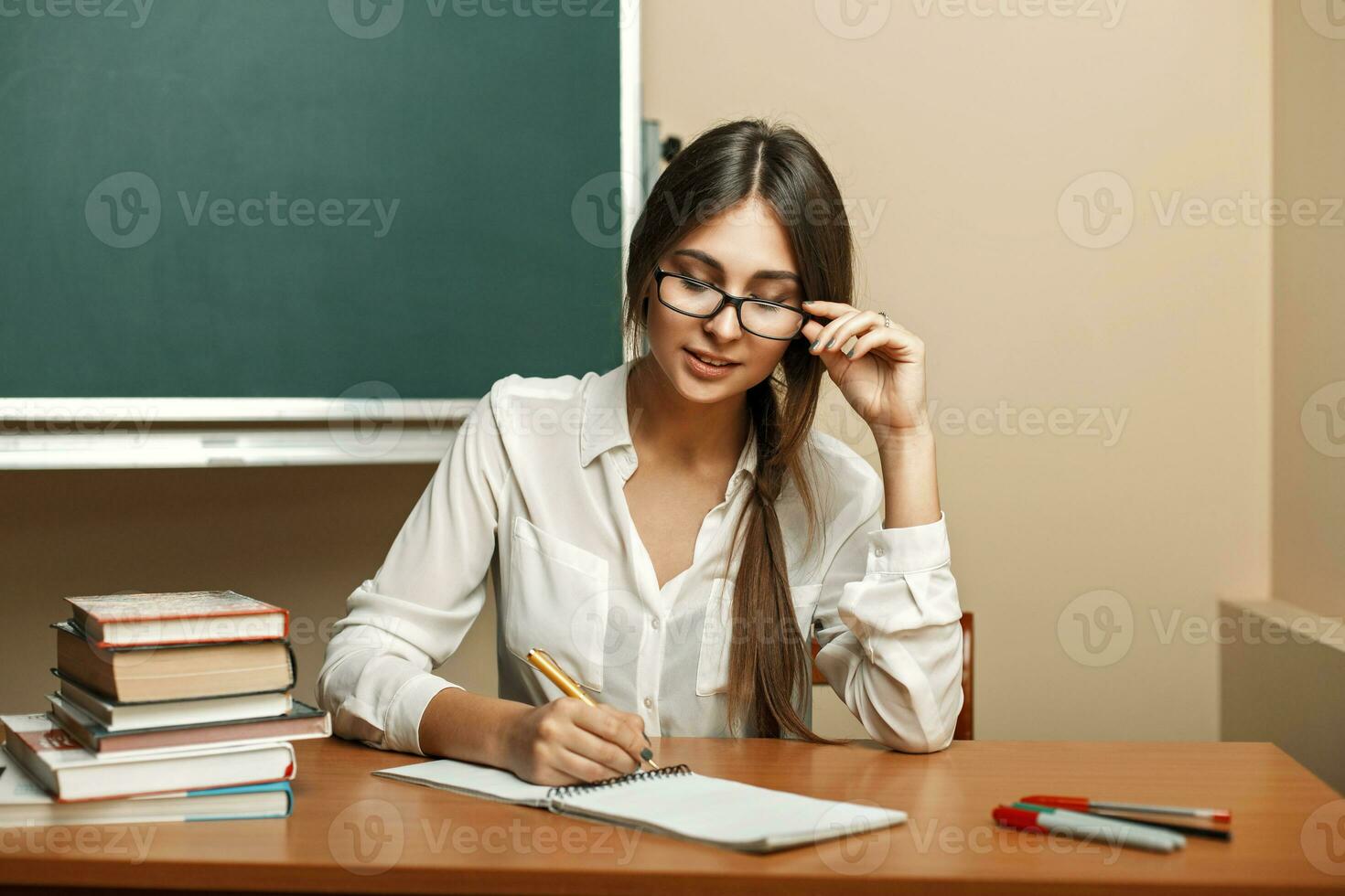 Beautiful young woman with glasses to study at university, reading books and writes in a notebook. photo