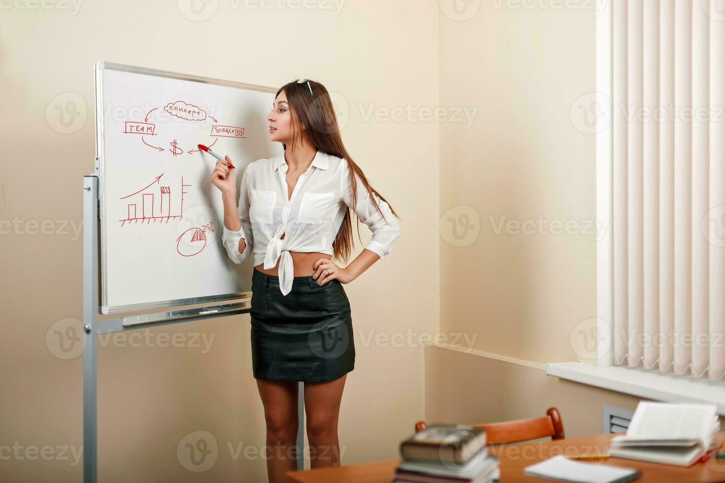 Beautiful young woman in an office writes with a red marker on the whiteboard. Development and Management photo