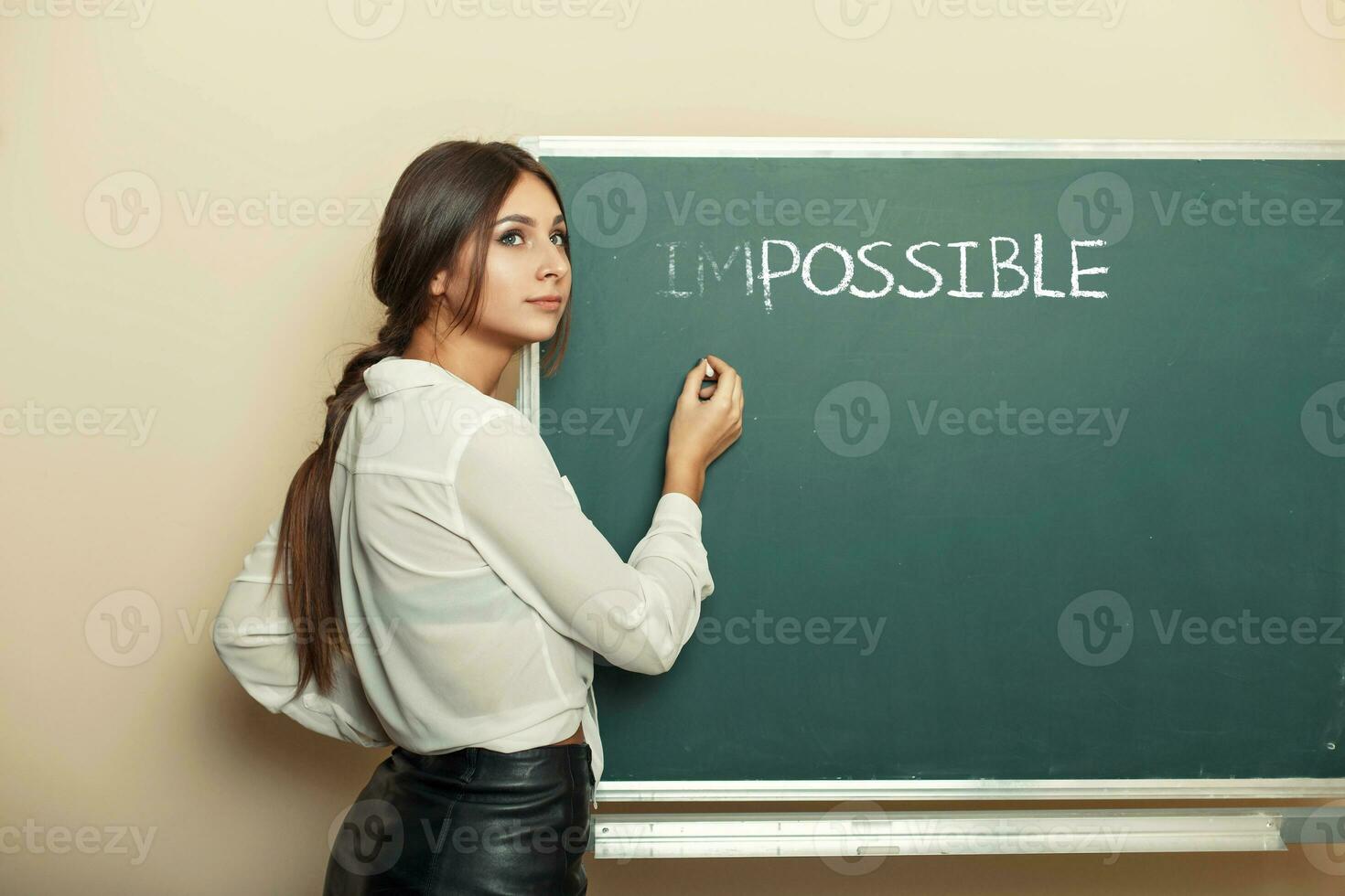 hermosa mujer escribe en un pizarra el palabra imposible. el concepto de posible. foto