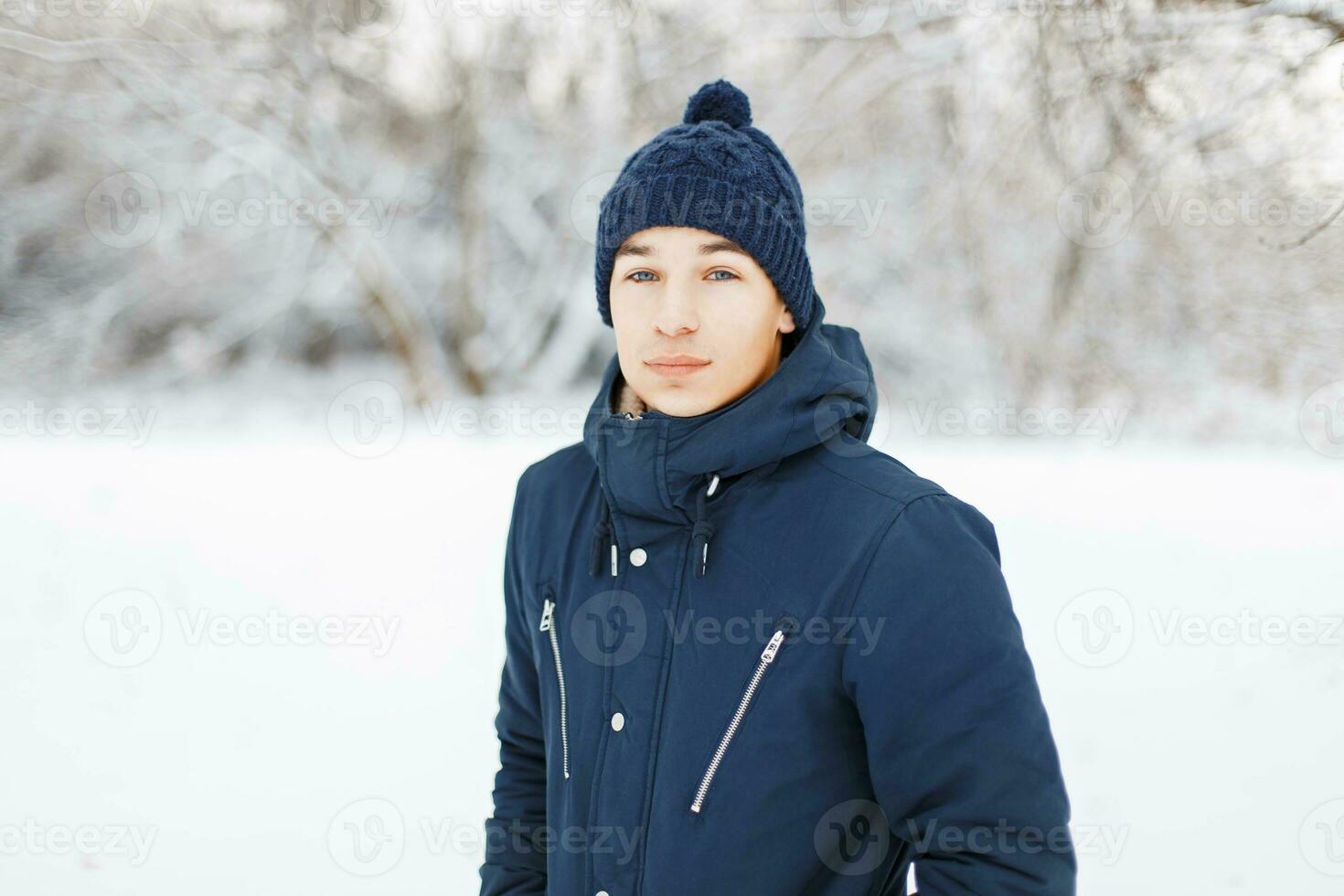 Young man in stylish winter clothes on a background of snowy park photo