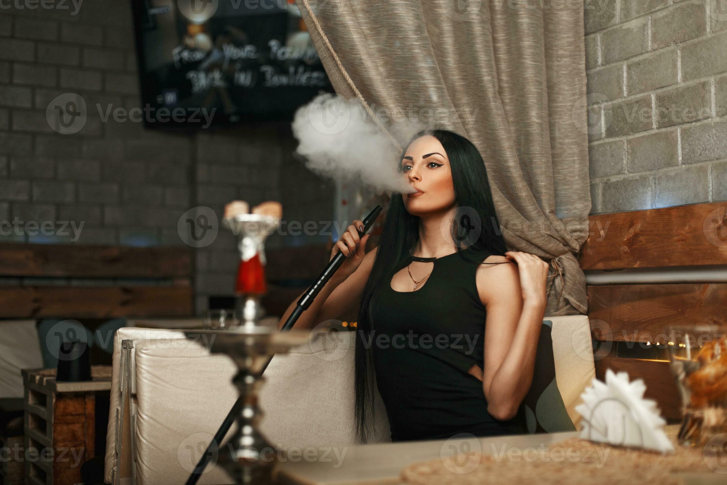 The beautiful girl smokes a hookah and lets the smoke. Woman resting in a bar 23334389 Stock