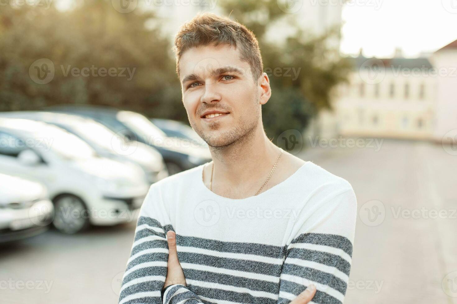 contento joven hermoso hombre en pie en el estacionamiento lote a puesta de sol foto