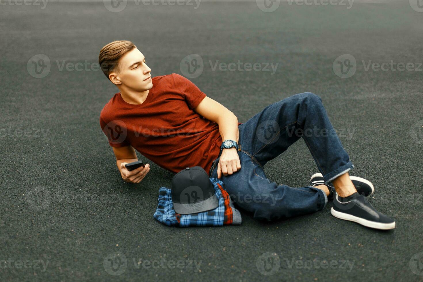 Handsome man with phone lying on the pavement and rests. photo