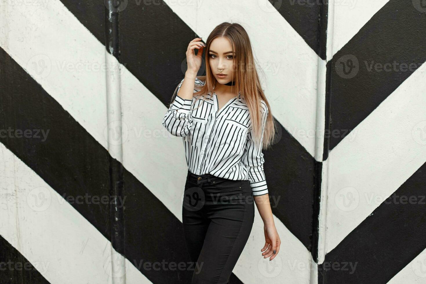 Beautiful young girl in fashionable blouse near the wall design with lines photo