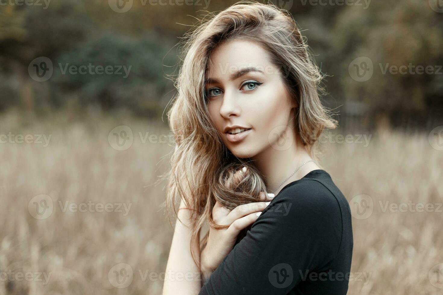 retrato de un joven mujer en un negro camisa en un antecedentes de naturaleza foto