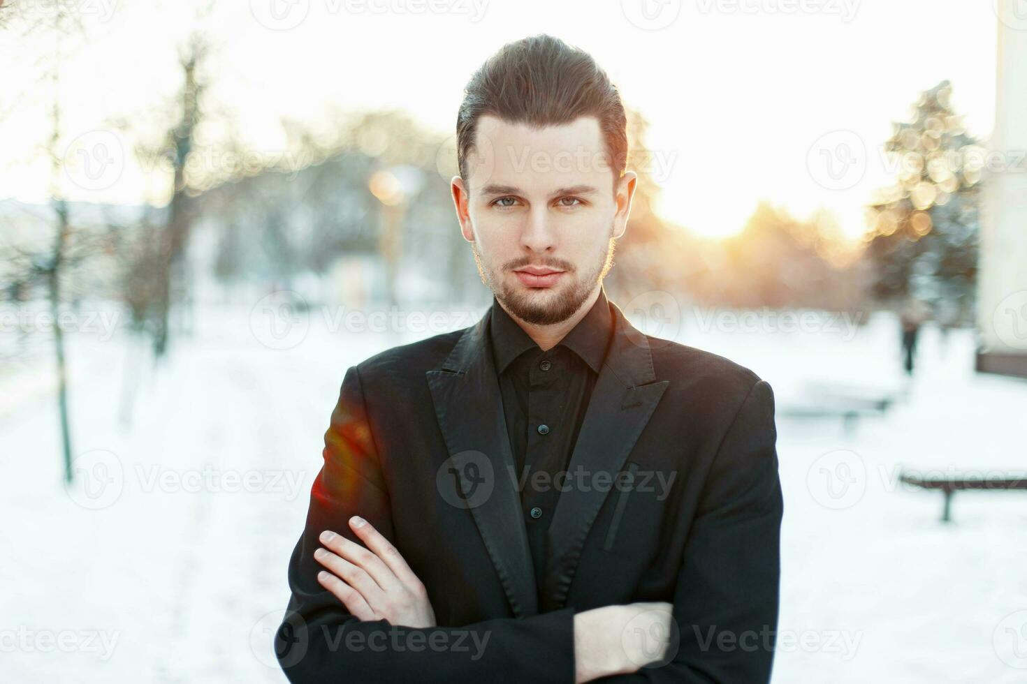 Handsome man in a black stylish suit on a sunset photo