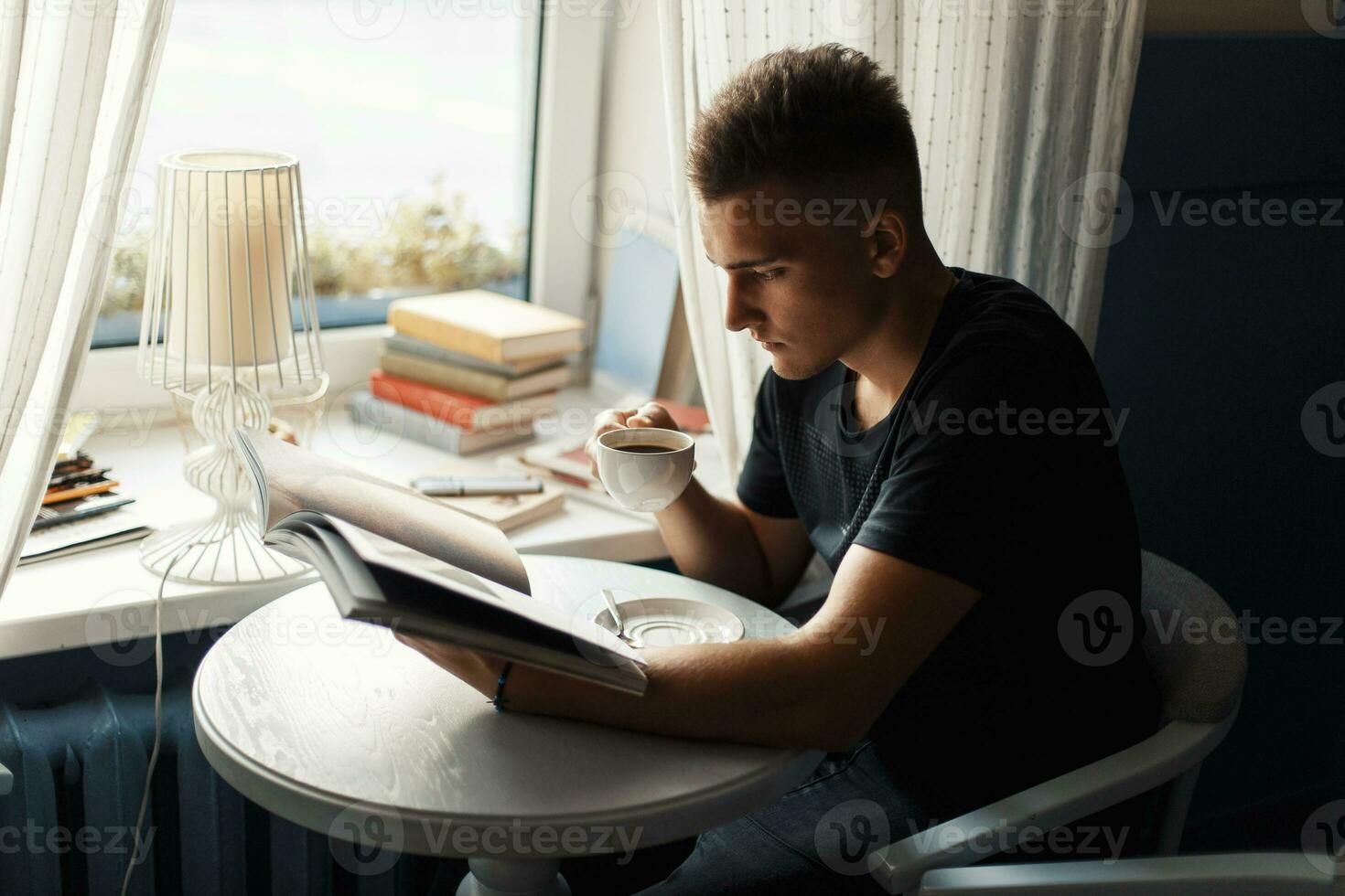 Handsome man drinking coffee and reads magazine in the cafeteria photo