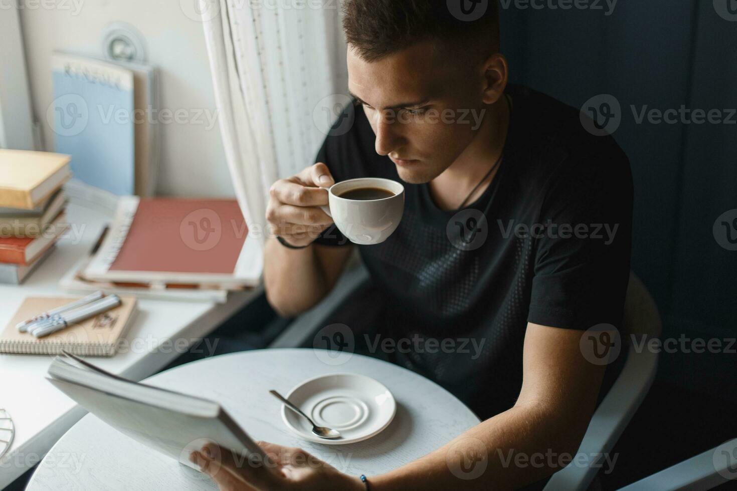 joven hombre leyendo un libro y Bebiendo café en un restaurante foto