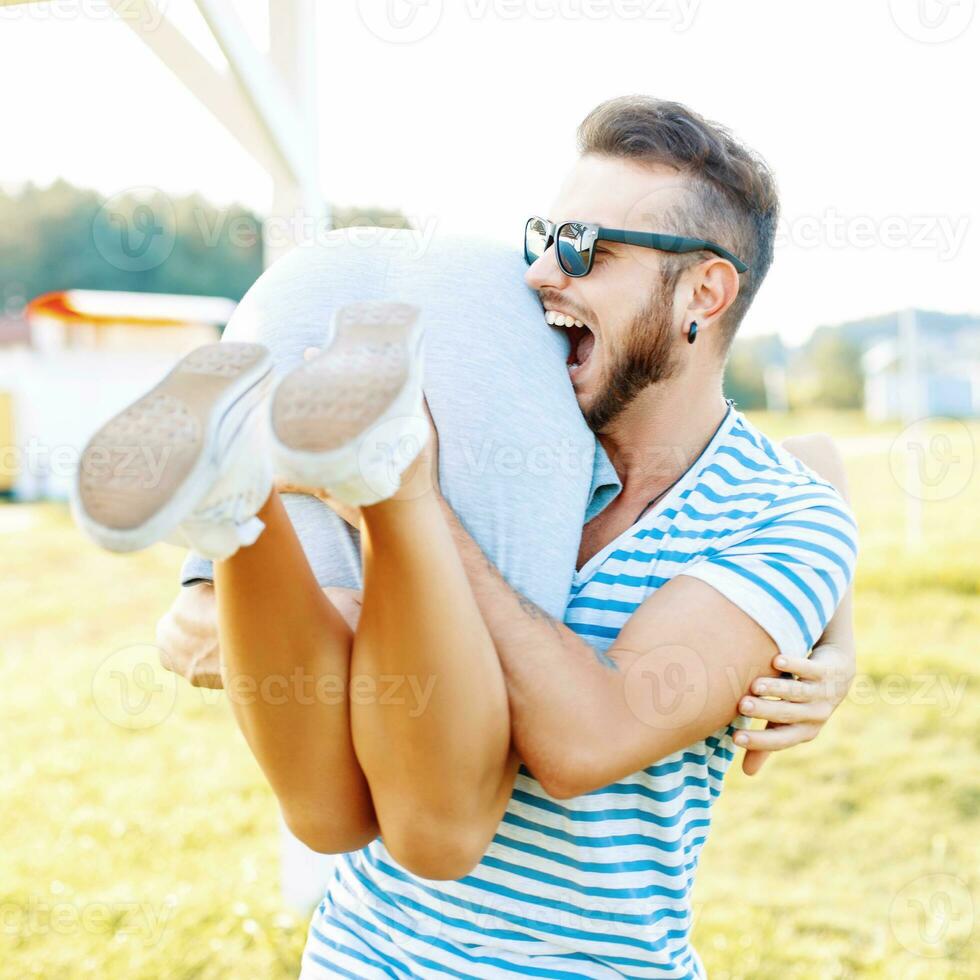 Young beautiful hipster couple relaxing on the beach. Handsome man and woman have fun on a summer day. Man bites the girl's ass photo
