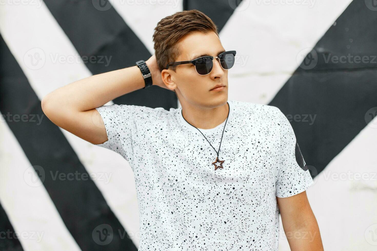 Stylish handsome man in sunglasses posing on background lines photo