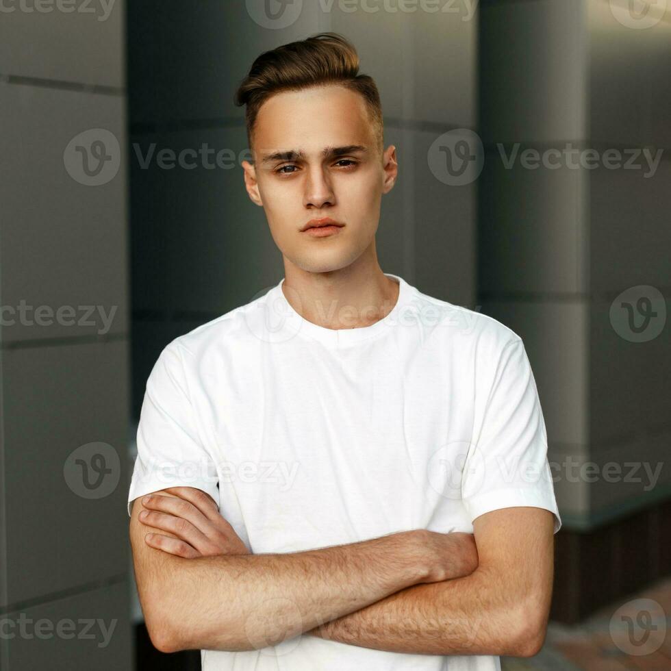 retrato de un hermoso hombre en un blanco camiseta posando mano en mano. foto