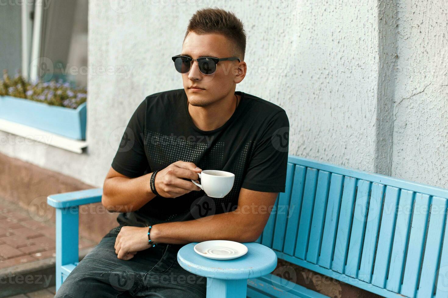 Handsome young man with coffee sitting on a bench. photo