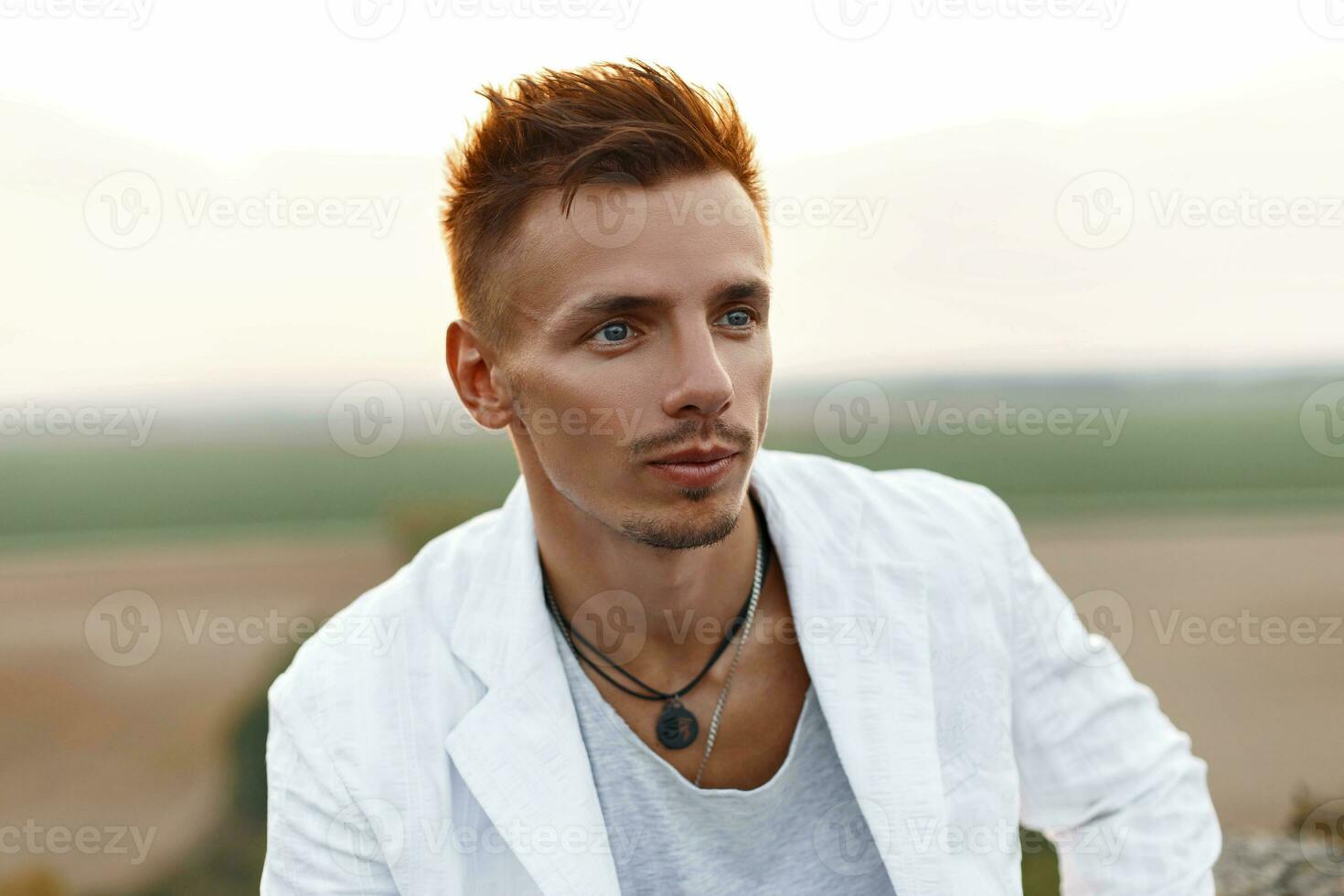 elegante hermoso hombre con pelo en un blanco vestido, al aire libre foto