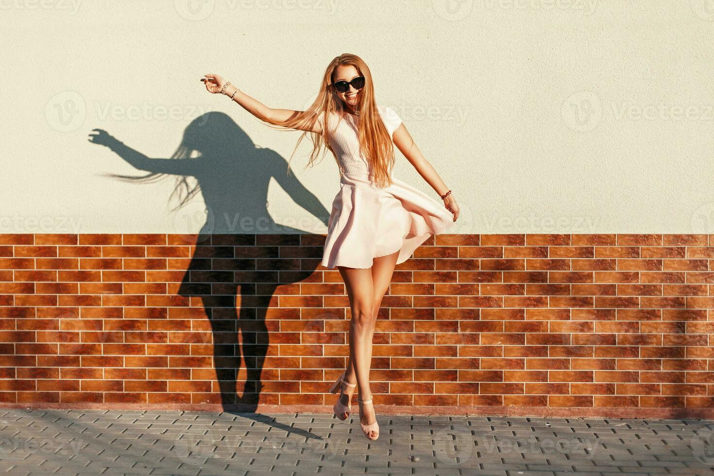 Beautiful young cheerful girl with a smile jumping near the wall. Have fun photo