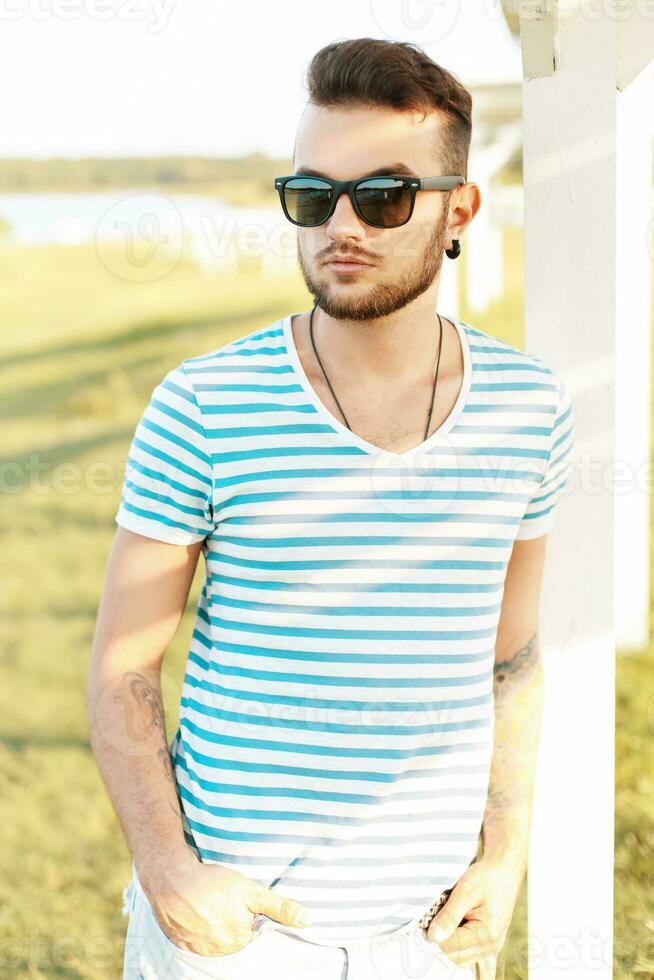 hermoso hombre en un elegante verano camiseta descansando en el playa. foto