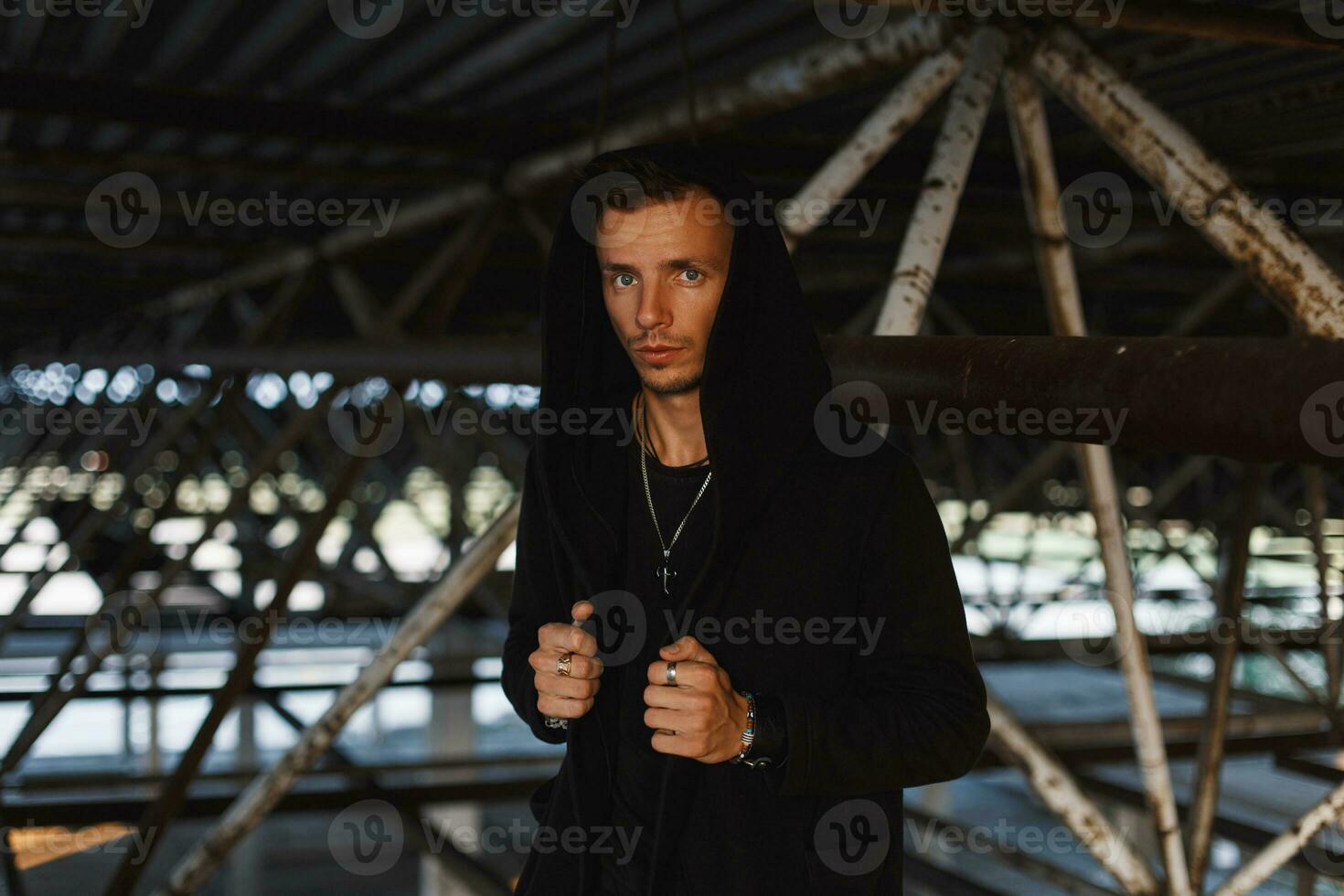 Handsome man in a black hood near metal pipes photo