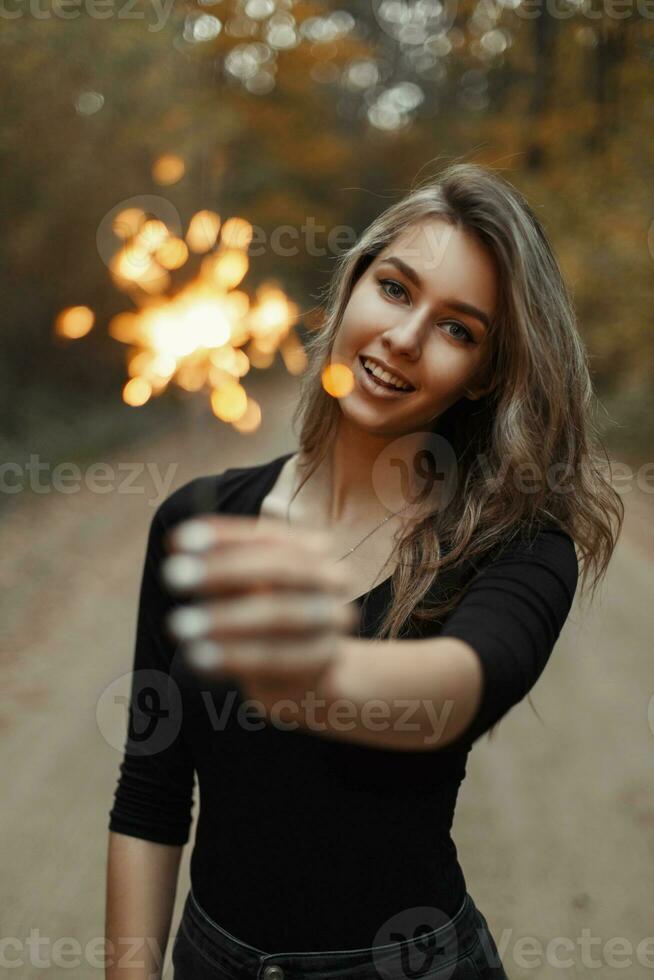 Cheerful beautiful woman with a smile, having fun with a sparkler. photo