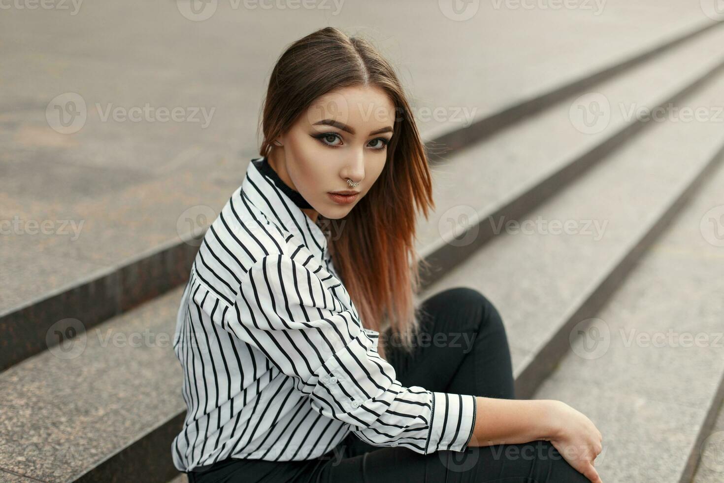 Young beautiful woman sitting on the steps and looking at the camera photo