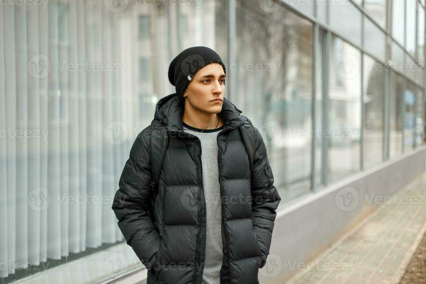 Handsome man in winter warm jacket with a backpack walking in the city photo