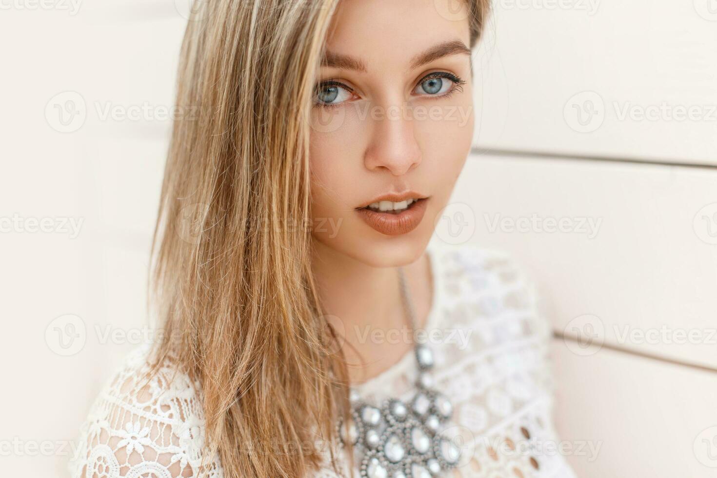 Portrait of a beautiful blond girl with blue eyes on the background of a wooden wall. photo