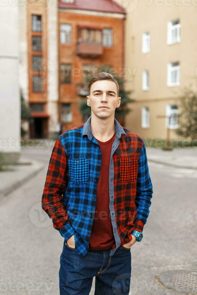 hermoso hombre en un a cuadros camisa en el antecedentes de edificios foto