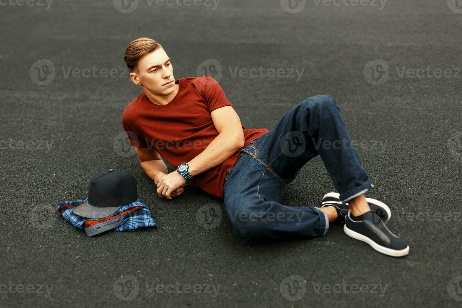 hermoso hombre en camiseta acostado en el piso. de moda camisa y béisbol gorra. foto