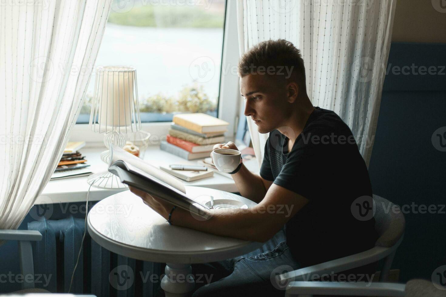 Handsome man with coffee reading a book. photo