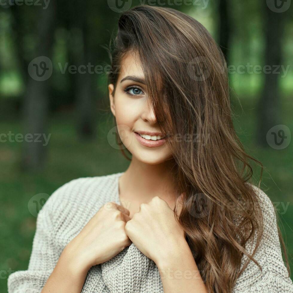 Beautiful portrait of a pretty young girl with the hairstyle smiling with a white smile in the park looking at the camera photo