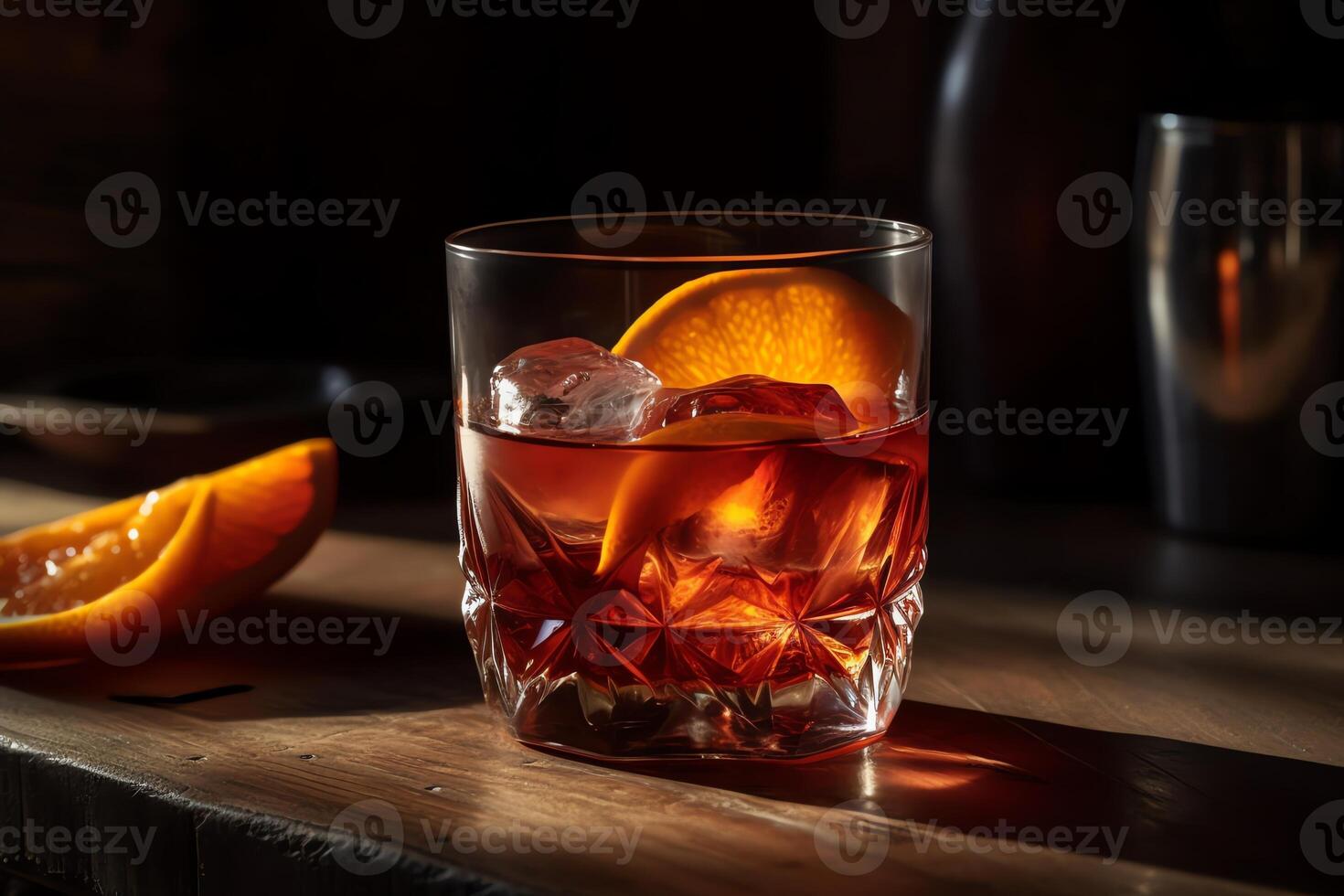 A handcrafted negroni drink complete with ice and an orange slice sitting on a wooden table in a vertical closeup. photo