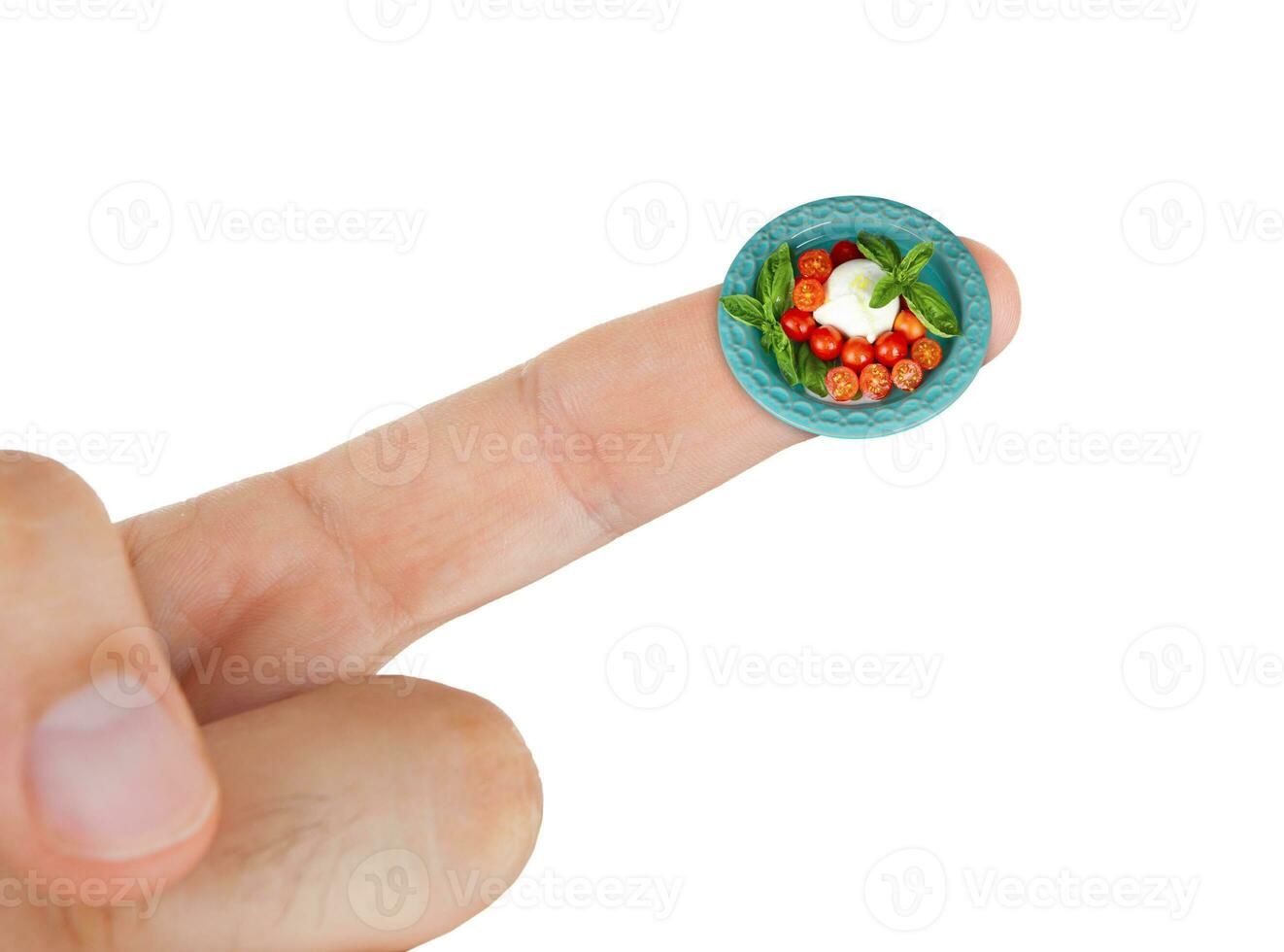 Dish with mozzarella and cherry tomatoes in miniature on index finger photo