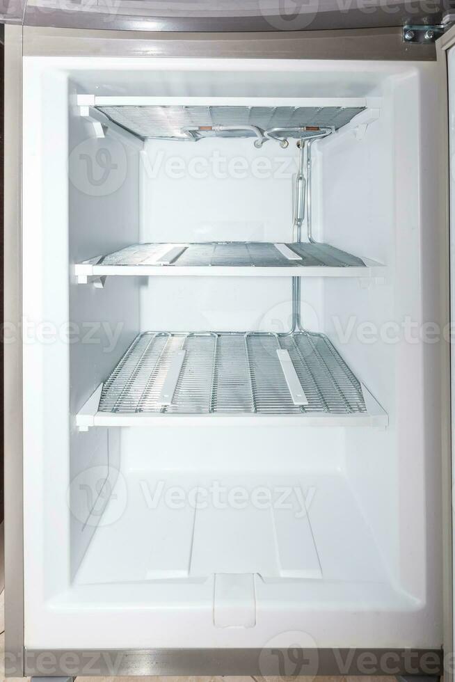 Empty and defrosted household freezer with open door. photo