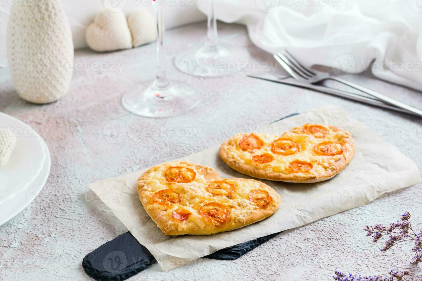 dos corazón conformado pizzas en papel en un conjunto mesa para San Valentín día celebracion foto