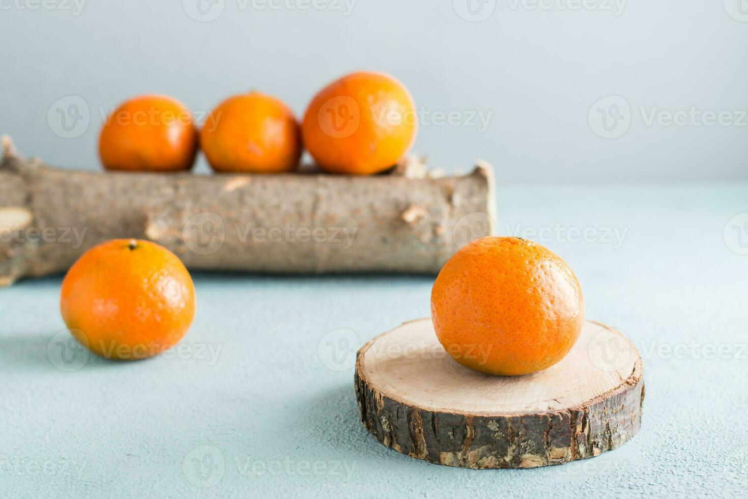 Ripe tangerines on a cut of a tree and tangerines on a log on a blue background. Eco-friendly fruits photo
