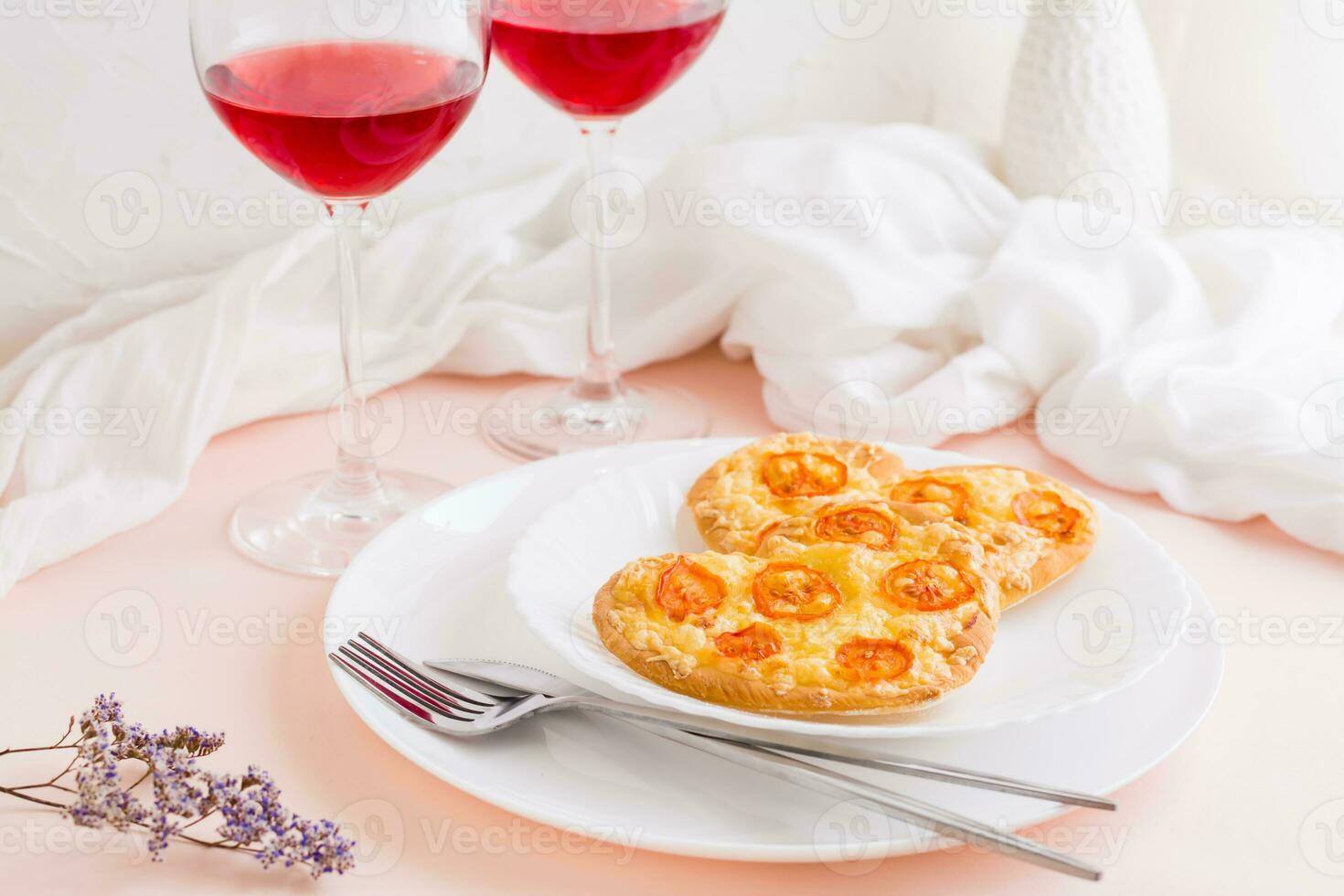 dos corazón conformado listo para comer pizzas en platos y lentes de vino en un conjunto mesa para San Valentín día celebracion foto