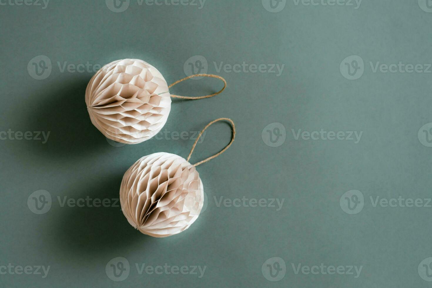 Two Christmas textured folded balls from craft paper on a green background. Copy space photo