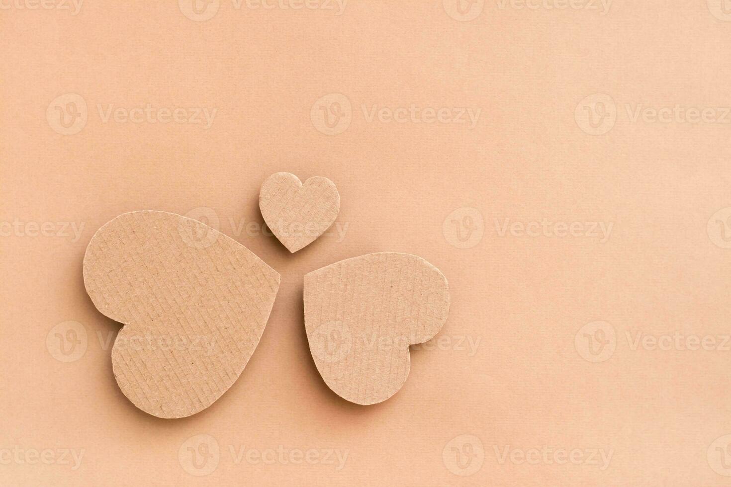 Family concept. Three cardboard hearts - dad, mom and child stand in a circle on a beige background. Top view. photo
