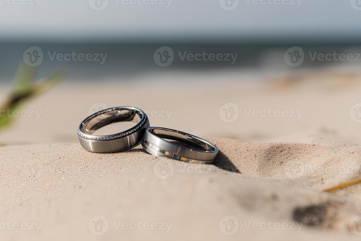 Two wedding rings in the sand on the background of a beach and sea. photo