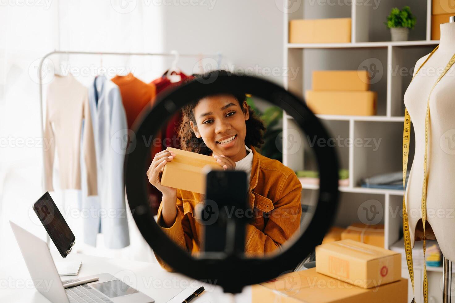 Fashion blogger concept, Young African women selling clothes on video streaming.Startup small business SME, using smartphone or tablet taking receive and checking photo